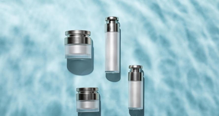 A top view of skincare bottles on a light blue water surface